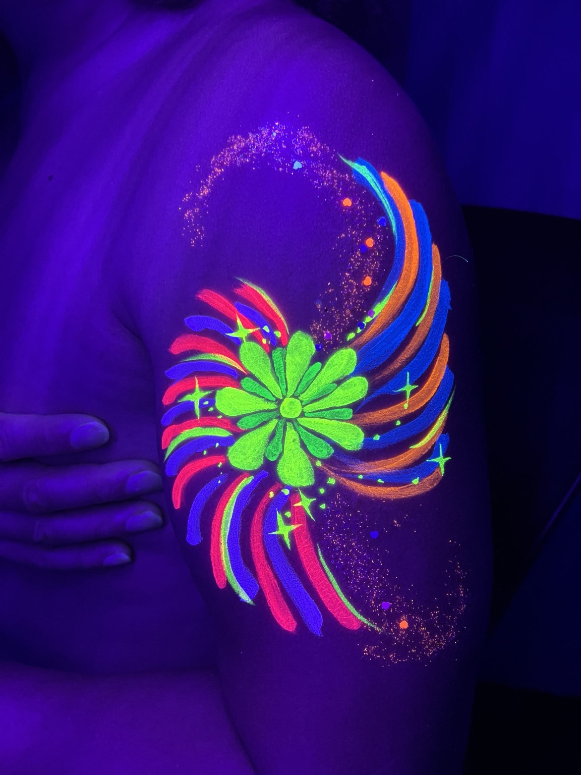 Glowing neon floral body painting under UV light